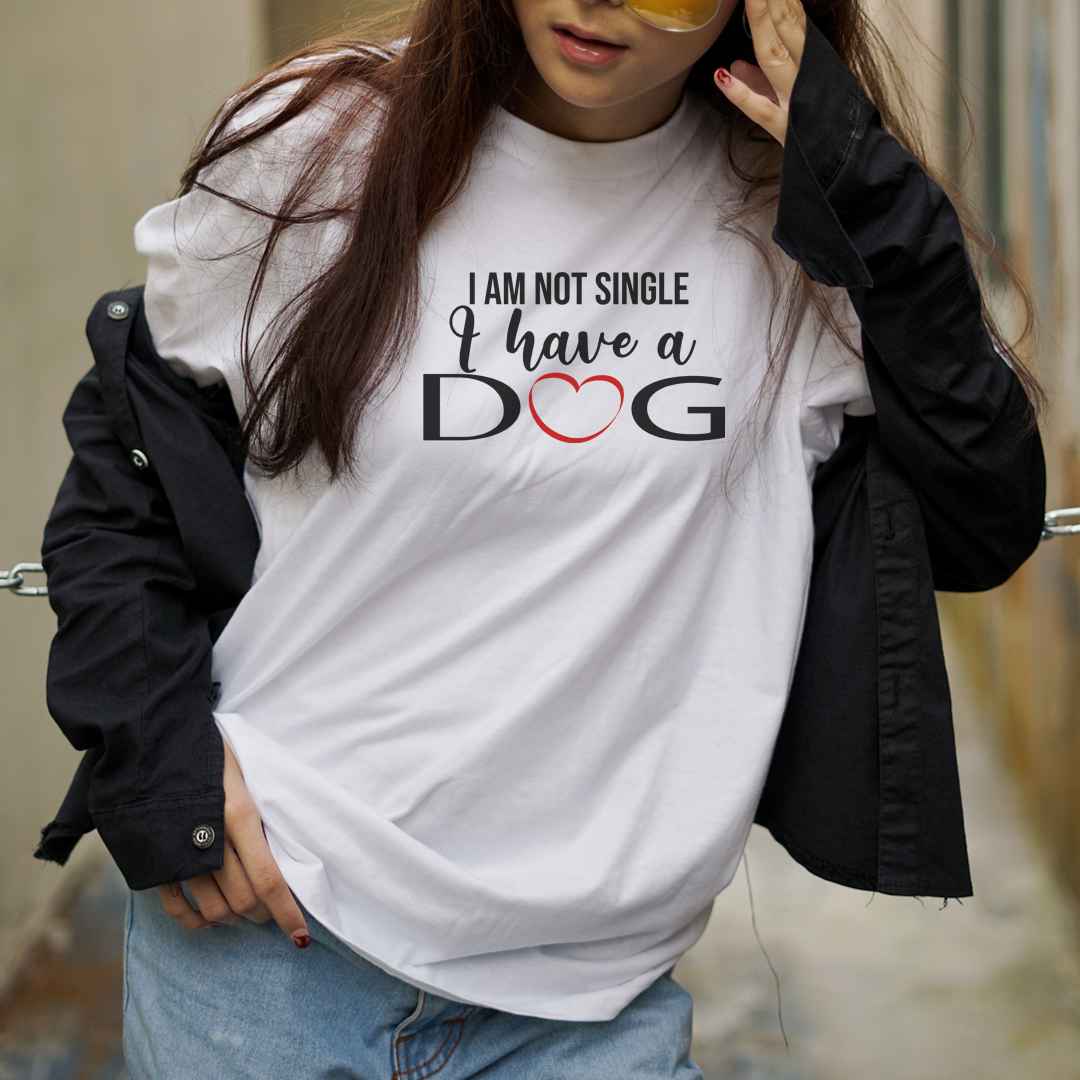 White cotton crew neck unisex  short sleeve tshirt, on the apparel is a graphic black/white text  saying " I am not single i have a dog" the letter O in dog is a red heart and "DOG" is in capital letters