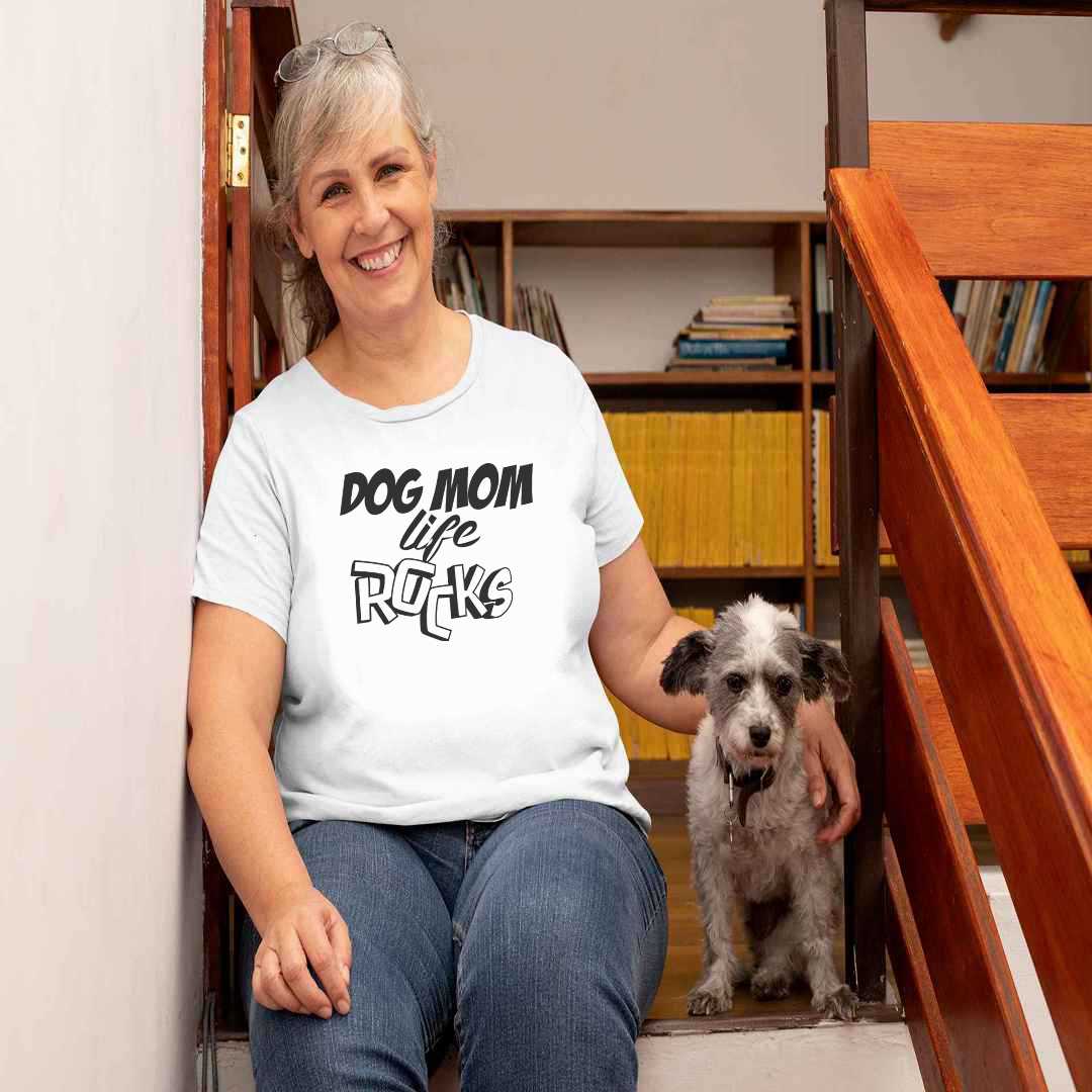  White cotton crew neck unisex  short sleeve tshirt, on the apparel is a graphic black text  saying "Dog Mom Life Rocks" the  text "rocks" is in 3D.