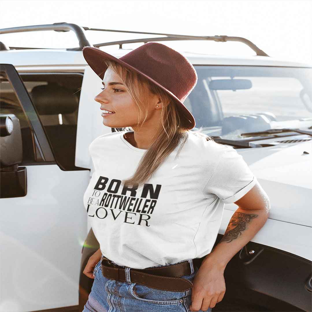 White cotton crew neck unisex  short sleeve tshirt, on the apparel is a black and white graphic print with the text BORN TO BE A ROTTWEILER in capital letters in different text styles