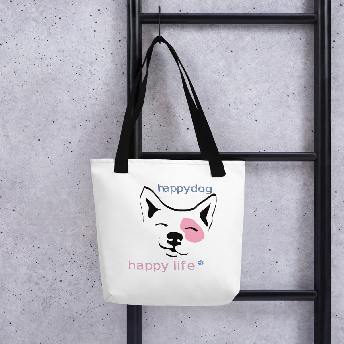 Uni-size 15"x15" white tote polyester canvas bag, with black stripped handle, features a cute Corgi face graphic print, complete with squinty eyes and a happy grin, with a uplifting message "happy dog, happy life" printed on the front. Bag hanging on a hook showing size and design.
