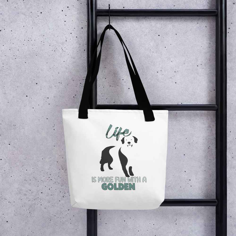 White spun canvas fabric tote bag , on the bag is a black one-line graphic print silhouette of a cute Golden Retriever dog standing with its tongue out. Above the dog is the text " LIFE" in cap and underneath the dog is the text " is more fun with a Golden " in cap"