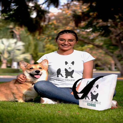 White spun canvas fabric tote bag , on the bag is a black one-line graphic print silhouette of a cute Welsh Corgi dog standing with its tongue out. Above the dog is the text " LIFE" in cap and underneath the dog is the text " is more fun with a Corgi " in cap" 