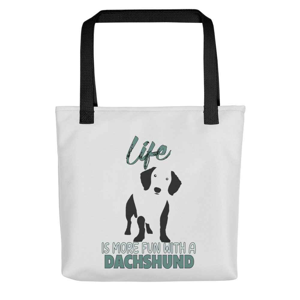 White spun canvas fabric tote bag , on the bag is a black one-line graphic print silhouette of a cute Dachshund dog standing with its tongue out. Above the dog is the text " LIFE" in cap and underneath the dog is the text " is more fun with a Dachshund " in cap"