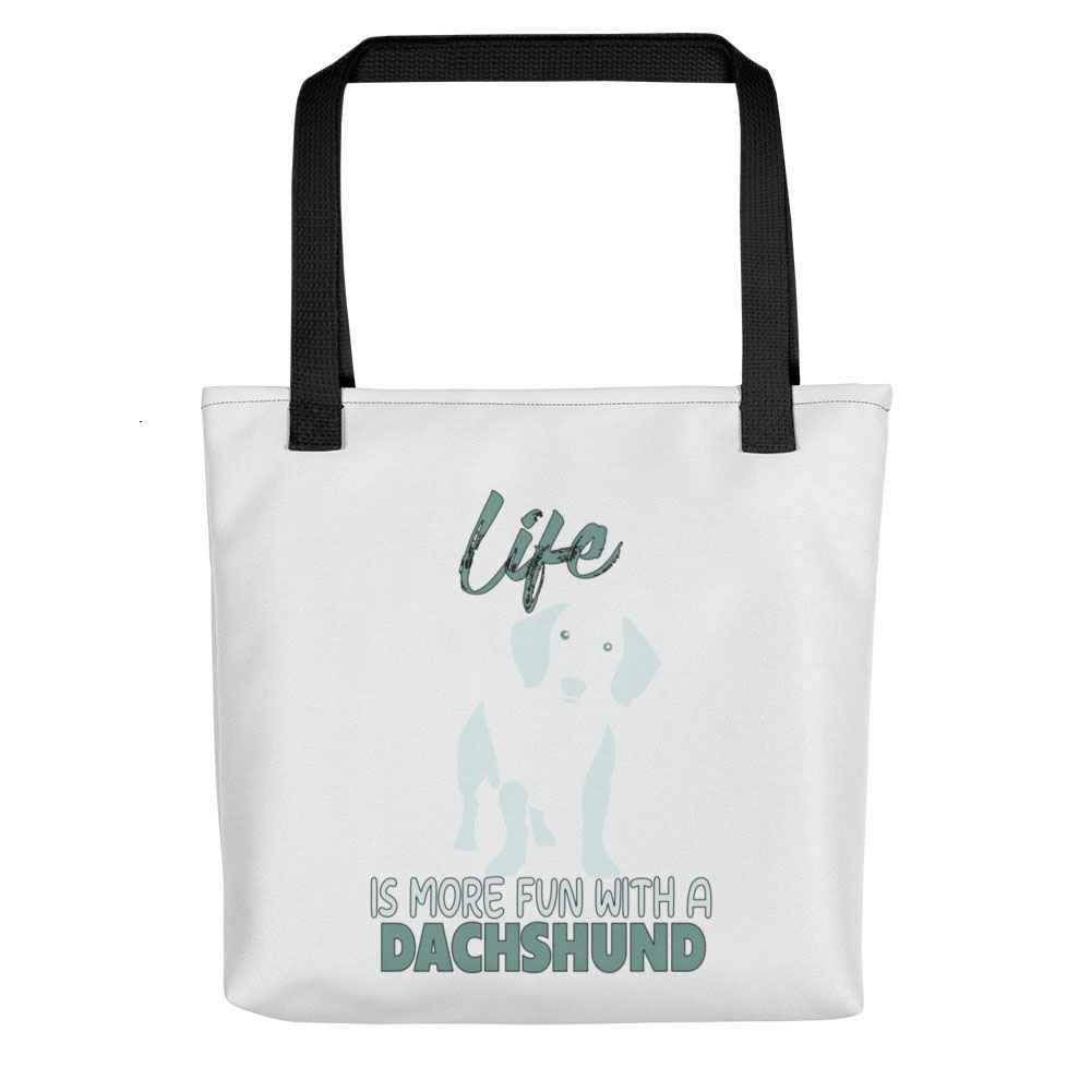 White spun canvas fabric tote bag , on the bag is a black one-line graphic print silhouette of a cute Dachshund dog standing with its tongue out. Above the dog is the text " LIFE" in cap and underneath the dog is the text " is more fun with a Dachshund " in cap"