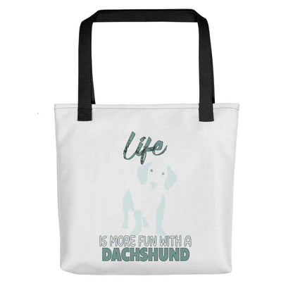 White spun canvas fabric tote bag , on the bag is a black one-line graphic print silhouette of a cute Dachshund dog standing with its tongue out. Above the dog is the text " LIFE" in cap and underneath the dog is the text " is more fun with a Dachshund " in cap"