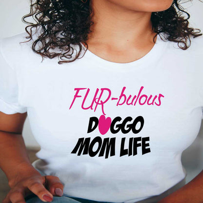 White cotton crew neck unisex  short sleeve tshirt, on the apparel is a graphic pink text  saying "fur-buluos"  below the the text "doggo mom life" the letter O in "Doggo" is a pink heart.