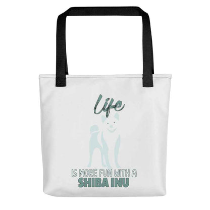 White spun canvas fabric tote bag , on the bag is a black one-line graphic print silhouette of a cute Shiba Inu standing with its tongue out. Above the dog is the text " LIFE" in cap and underneath the dog is the text " is more fun with a Shiba Inu " in cap