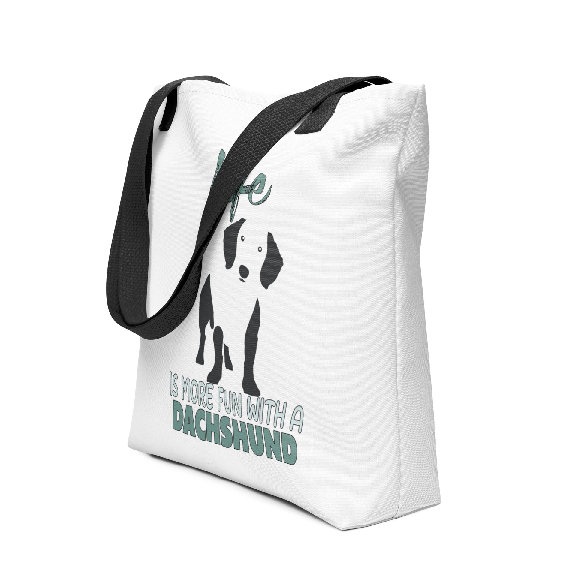 White spun canvas fabric tote bag , on the bag is a black one-line graphic print silhouette of a cute Dachshund dog standing with its tongue out. Above the dog is the text " LIFE" in cap and underneath the dog is the text " is more fun with a Dachshund " in cap"