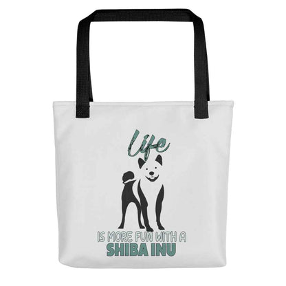 White spun canvas fabric tote bag , on the bag is a black one-line graphic print silhouette of a cute Shiba Inu standing with its tongue out. Above the dog is the text " LIFE" in cap and underneath the dog is the text " is more fun with a Shiba Inu " in cap