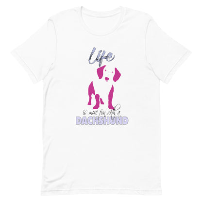 White cotton crew neck unisex  short sleeve tshirt, on the apparel is a graphic print silhouette of a cute adorable Dachshund standing , the dog silhouette is in pink color, above the dog is the text " Life" written in tilted purple graphic letter, below is the text " is more fun with a Dachshund" in capital letter, the text "Dachshund" stands out with its pink color