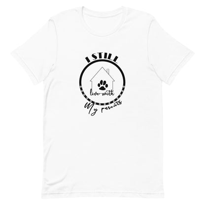 White cotton crew neck unisex  short sleeve tshirt, on the apparel is a graphic black circle with several dog paws, inside the circle is a graphic house with its front with chimney, the house got the text" live with" above the circle is the text " I still" and at bottom at the the house the text "my parents"