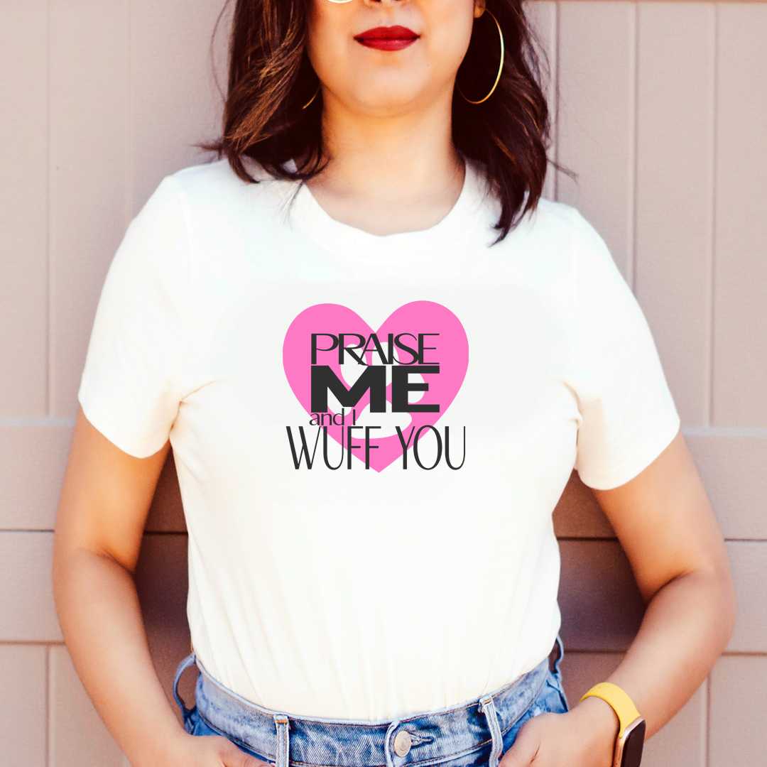 White cotton crew neck unisex  short sleeve tshirt, on the apparel is a graphic pink heart with a paw, on top of the heart is the text " praise me and i wuff you"